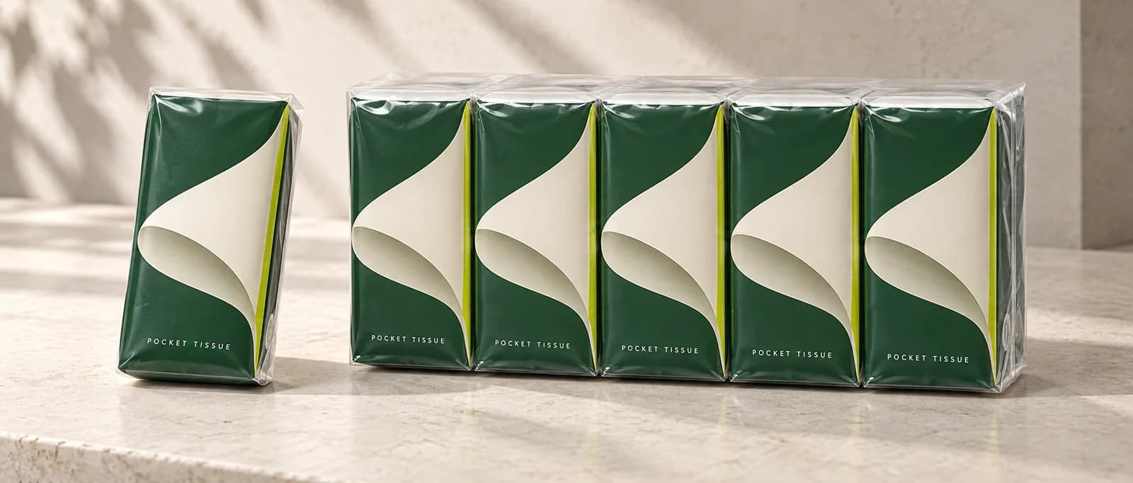 AI packaging concept showing one green pocket tissue pack beside five matching packs in clear outer film