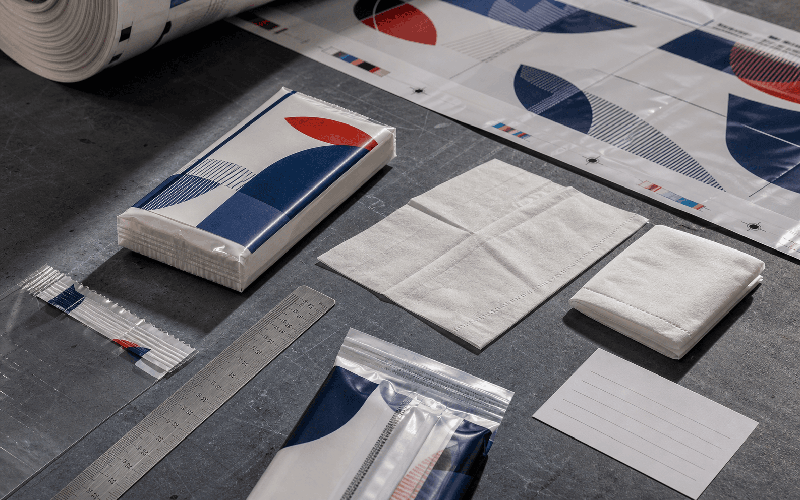 Pocket tissue quotation and specification workbench with soft pack, printed film proof, folded tissues, ruler, opening detail, and crimped end seal.