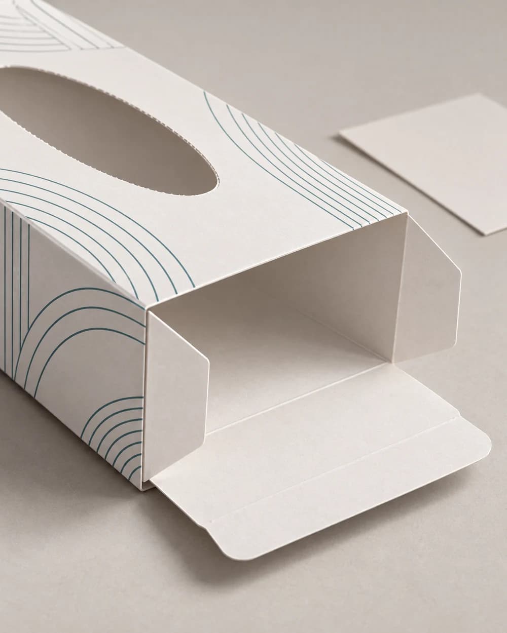 AI concept showing the open end flaps and creases of a white and blue folding tissue carton beside a flat paperboard offcut