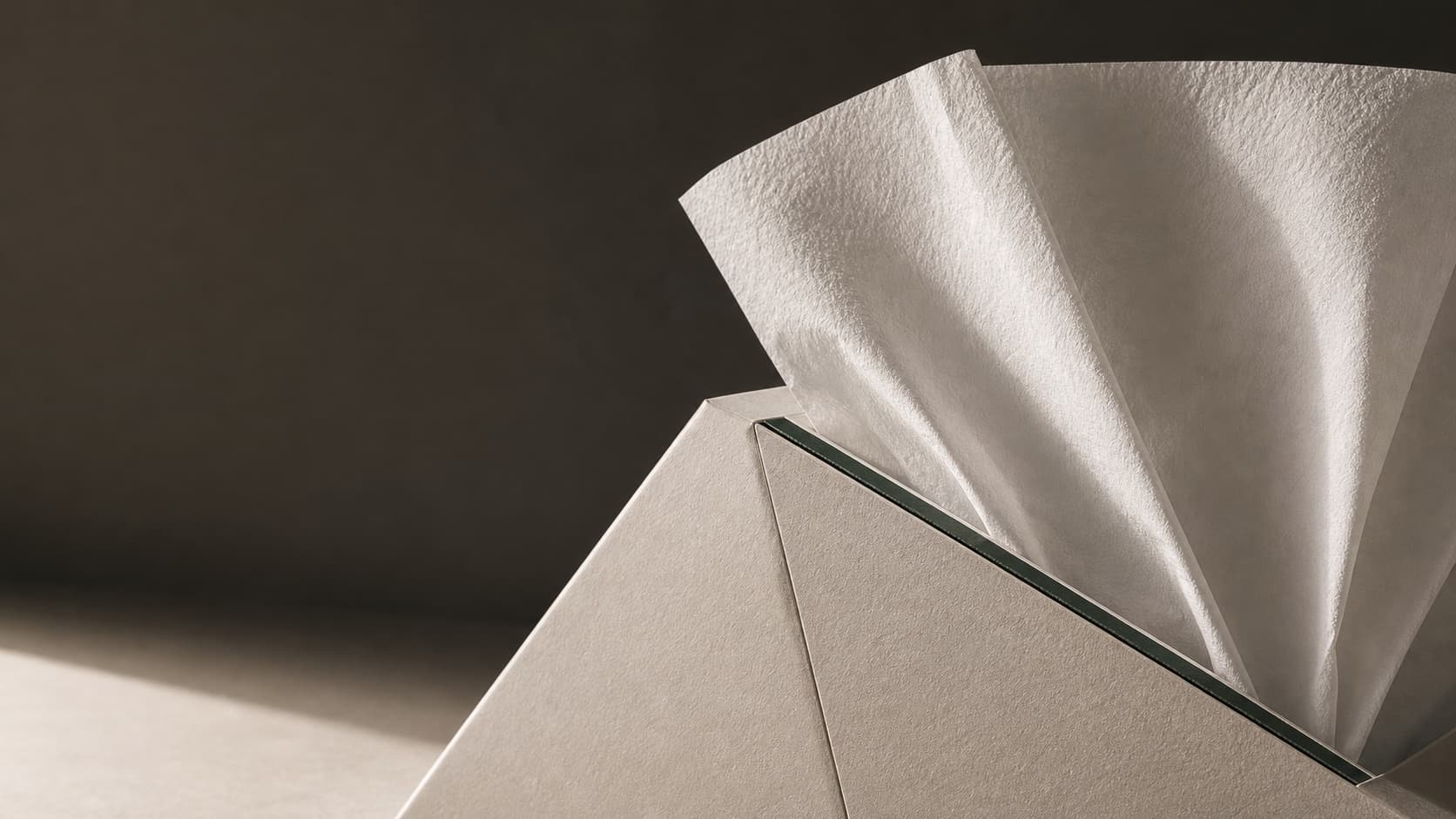 Editorial close-up of premium tissue packaging with paper texture and a deep sage edge detail